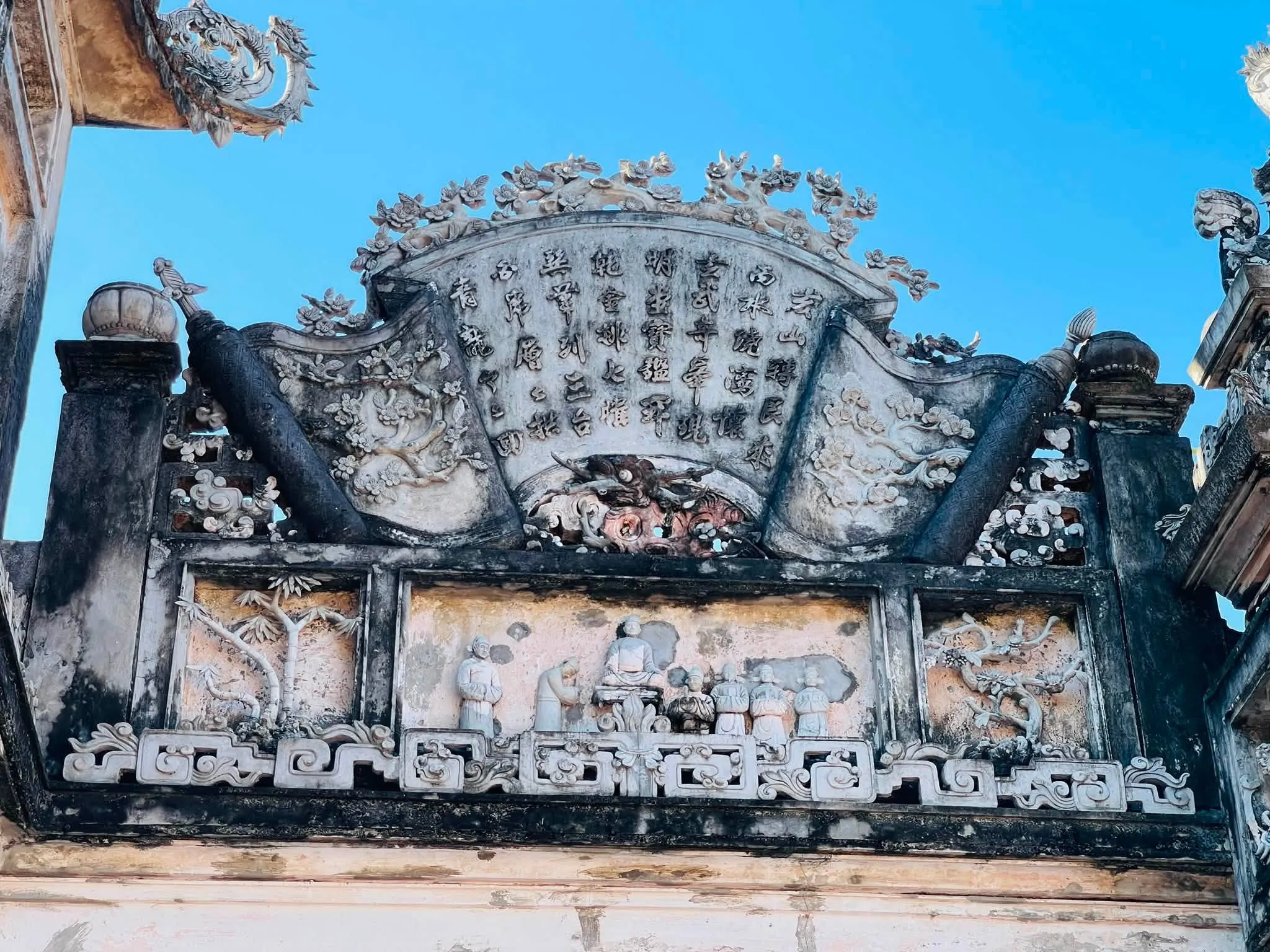 Trán cổng nghi môn đắp cuốn thư hình quạt và phù điêu tích cổ.