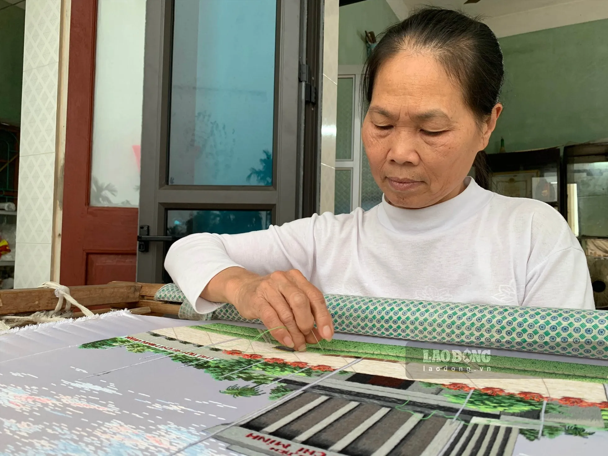 Nghệ nhân Phạm Thị Hòa bên sản phẩm thêu sắp hoàn thiện