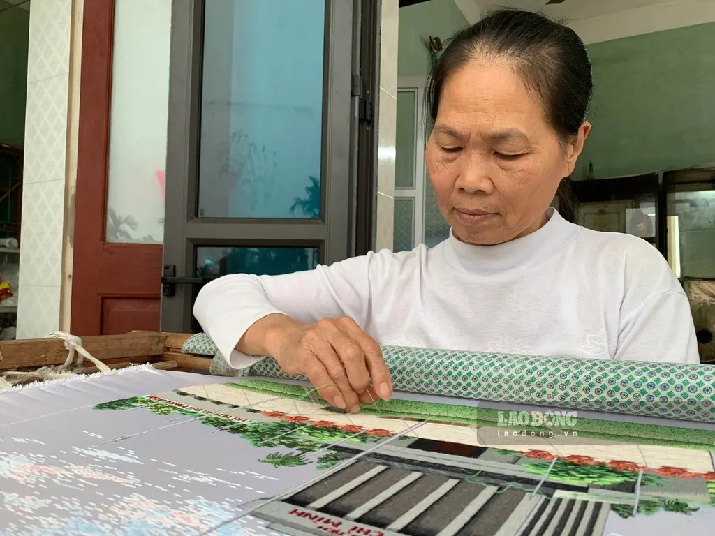 Nghệ nhân Phạm Thị Hòa bên sản phẩm thêu sắp hoàn thiện