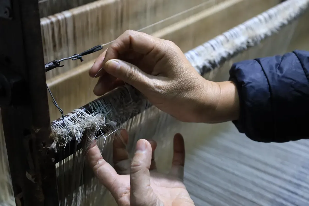 Công đoạn mắc sợi lên khung dệt the lụa La Khê
