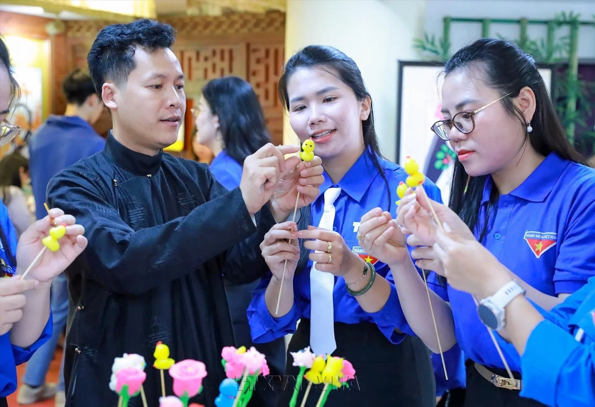 Nghệ nhân Đặng Văn Hậu (áo đen) hướng dẫn các đoàn viên thanh niên trải nghiệm làm tò he