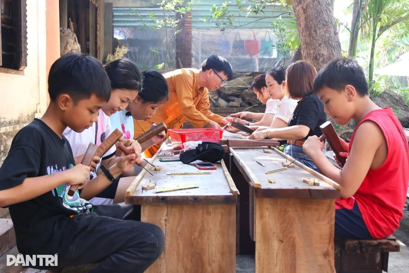 Nghệ nhân Huỳnh Sướng hướng dẫn du khách trải nghiệm chạm khắc mộc tại cơ sở
