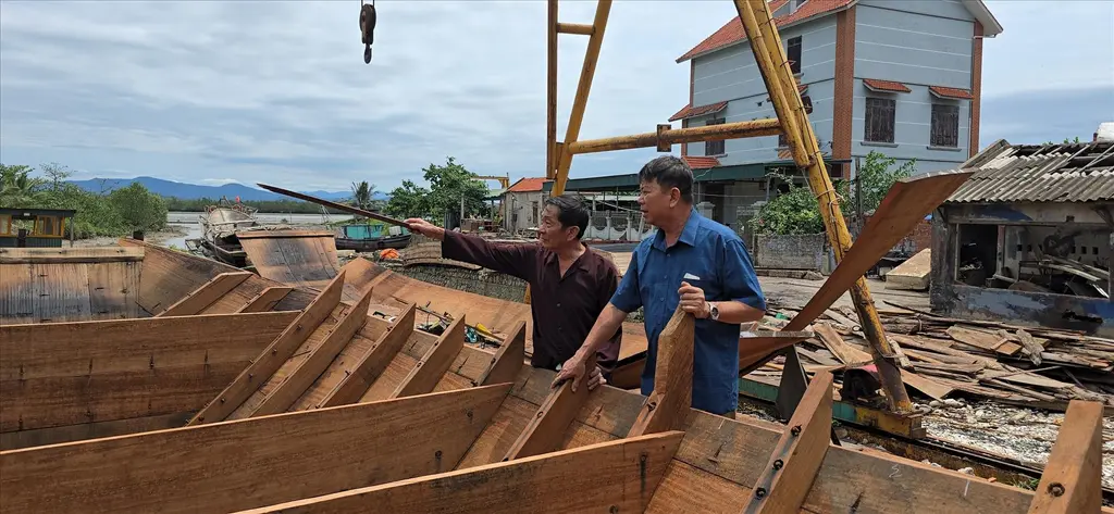 Nghệ nhân Chắn cùng con trai trao đổi các thông số về con thuyền ba vách đang trong quá trình hoàn thiện.