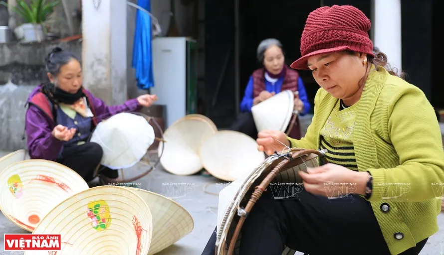 Những người phụ nữ đang thực hiện công đoạn hoàn thiện chiếc nón lá Vĩnh Thịnh.