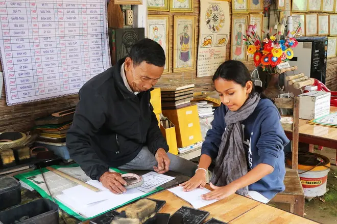 Nghệ nhân Kỳ Hữu Phước(bên trái) hướng dẫn du khách nước ngoài trải nghiệm các công đoạn in tranh