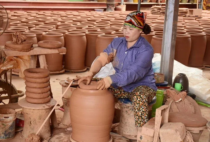 Nghệ nhân đang miệt mài tạo hình chum gốm bằng tay tại làng gốm Phù Lãng