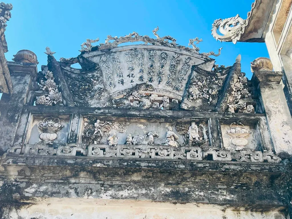 Trán cổng nghi môn đắp cuốn thư hình quạt và phù điêu tích cổ.