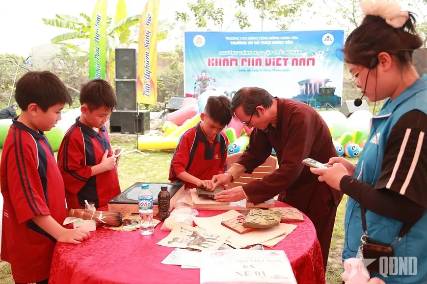 Nghệ nhân Nguyễn Hữu Quả tận tình hướng dẫn học sinh từng thao tác in mộc bản