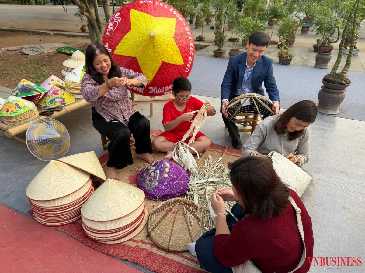 Nghệ nhân Tạ Thu Hương (áo hoa tím) đang hướng dẫn du khách làm nón