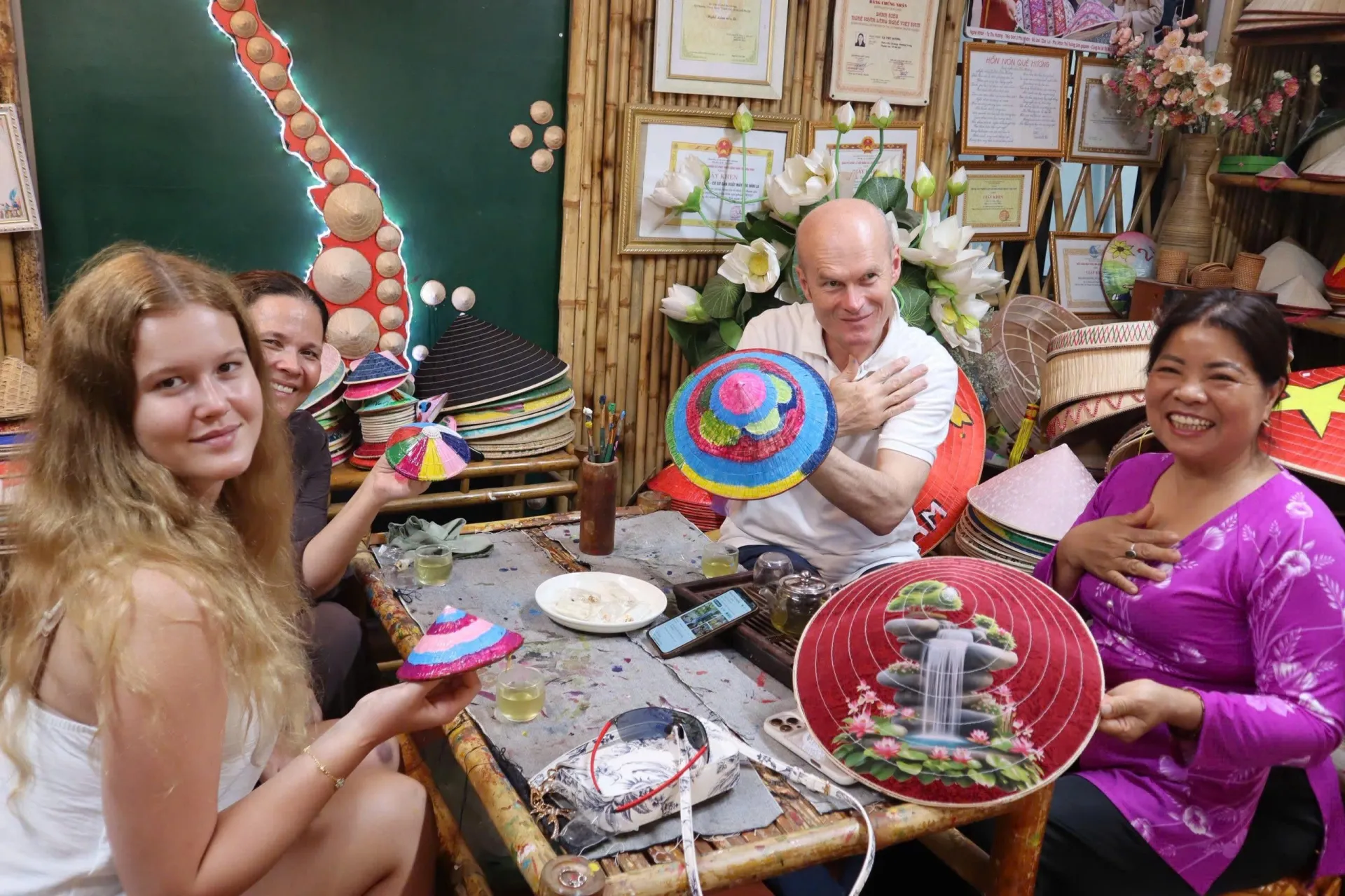 Những chiếc nón lá mang dấu ấn cá nhân được du khách hoàn thiện sau buổi trải nghiệm cùng nghệ nhân Tạ Thu Hương (bên phải)