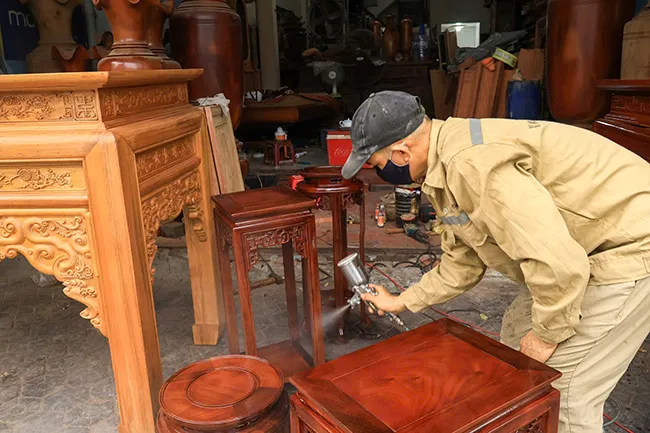 Người thợ tỉ mỉ sơn phủ bóng cho chiếc ghế trước khi xuất xưởng