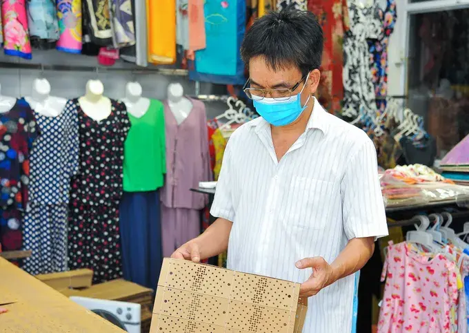 Ông Đỗ Văn Hiển kiểm tra bìa cứng sau khi máy đục tự động hoàn thành công đoạn