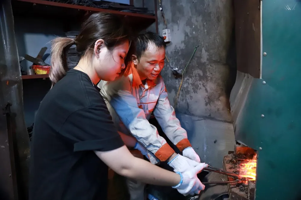 Nghệ nhân Lê Ngọc Lâm tận tình hướng dẫn một bạn trẻ luyện lửa cho lưỡi dao Đa Sỹ