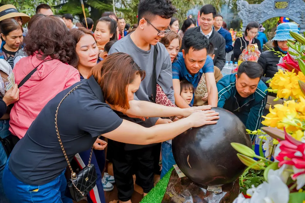 Du khách đặt tay lên quả cầu bằng đá để lấy may mắn tại Lễ hội Đền Nưa- Am tiên