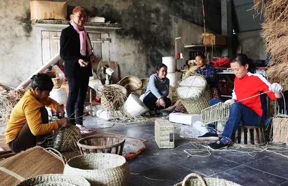 Nghệ nhân Ưu tú Trần Thị Việt (người đứng) động viên người lao động tại Công ty TNHH xuất khẩu Việt Trang