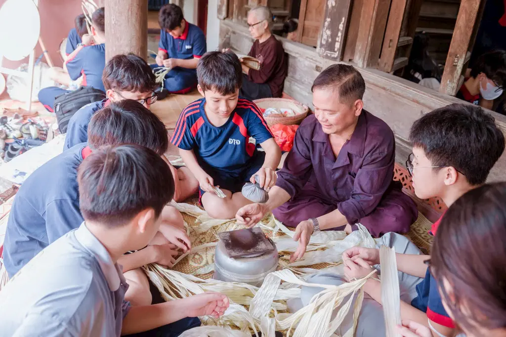 Nghệ nhân Lê Văn Tuy (áo nâu) đang dạy nghề cho các bạn nhỏ