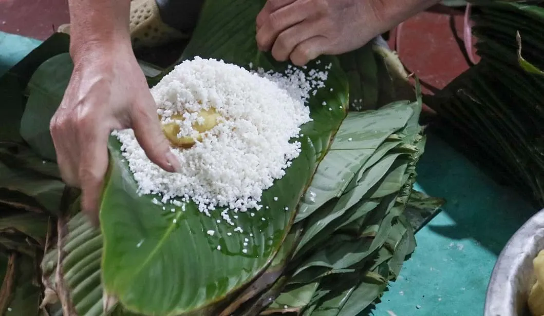 Người dân làng Tranh gói bánh bằng tay.
